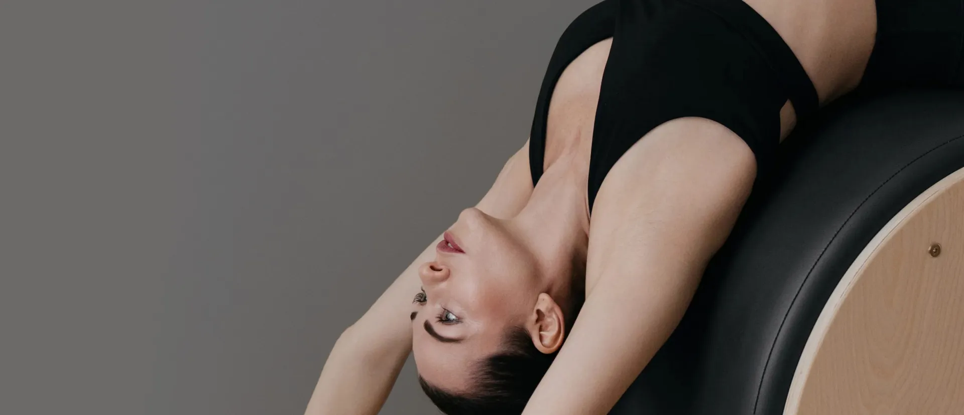 Kobieta wykonująca ćwiczenie rozciągające na beczce do pilatesu
